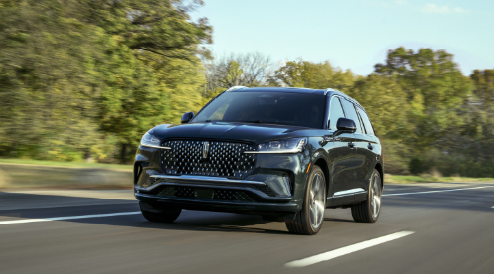 A 2025 Lincoln Black Label Aviator® SUV is being driven down a road lined with trees. | Doggett Lincoln of Beaumont in Beaumont TX
