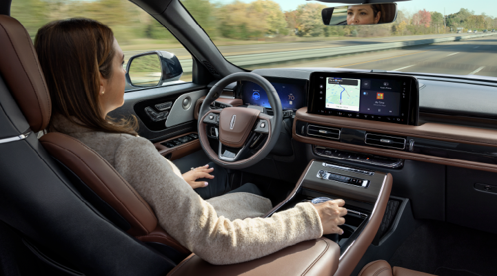 A woman is seen sitting in the driver’s seat of her 2025 Lincoln Aviator® SUV with her hands off the steering wheel. | Doggett Lincoln of Beaumont in Beaumont TX