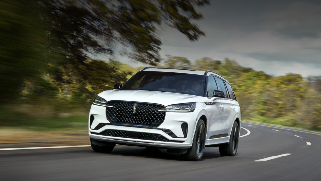 A white 2025 Lincoln Aviator® SUV is being driven down a road lined with trees. | Doggett Lincoln of Beaumont in Beaumont TX