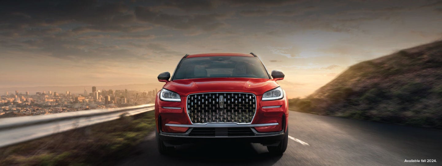A 2025 red Lincoln Corsair® SUV is being driven down a road at sunset. | Doggett Lincoln of Beaumont in Beaumont TX