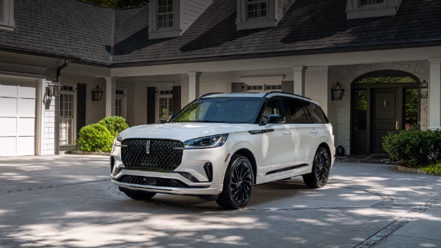 A white 2026 Lincoln Aviator® SUV is parked in the driveway of a luxury home. | Doggett Lincoln of Beaumont in Beaumont TX